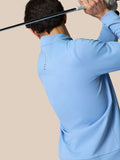 Back view of a man wearing a sky blue golf quarter zip top with stand collar and Castore branding.