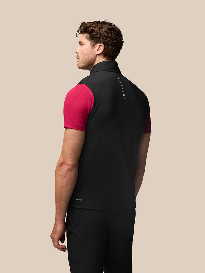 Rear view of a man in a black Golf Pinnacle Gilet over a red top, with Castore branding along the collar.