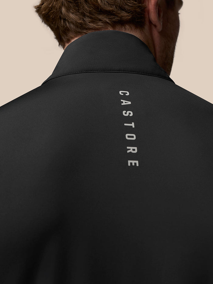 Back view of black golf gilet with vertical Castore branding along the upper back.