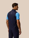 Side view of male model wearing navy Pinnacle Gilet over a light blue polo with back branding on the collar.