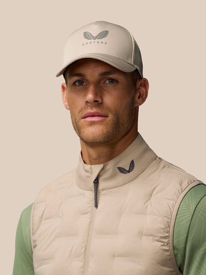Close up of a male model wearing Mushroom Golf Pinnacle Lightweight Hybrid Gilet with funnel collar and Castore logo at the collar