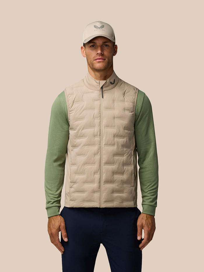 Male model wearing Mushroom Golf Pinnacle Lightweight Hybrid Gilet with cap, featuring the front zip and quilted panel