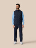 Male model wearing Golf Pinnacle Gilet Midnight Navy with stand collar and sleeveless silhouette over light blue sleeves