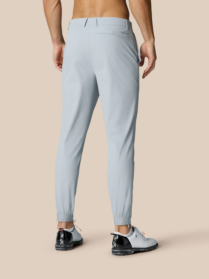 Back view of model wearing Golf Pinnacle 34in Trousers in Mid Grey with belt loops and branding at right thigh and rear