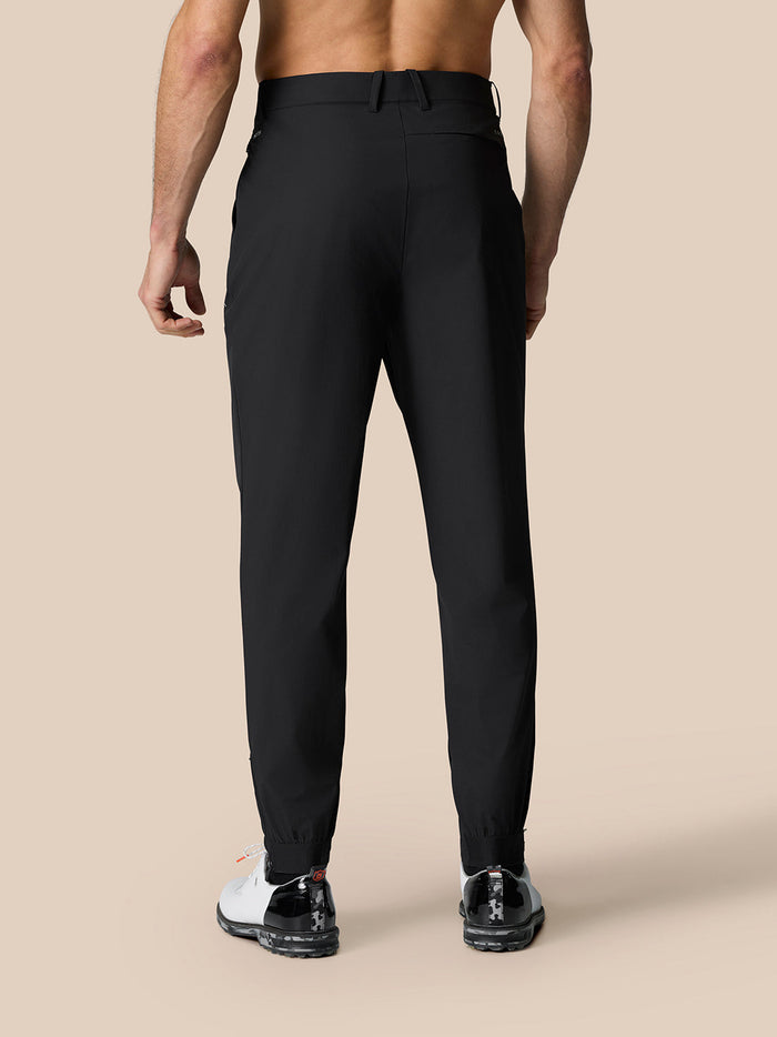 Back view of black golf trousers showing a logo on the right rear and elastic cuffs