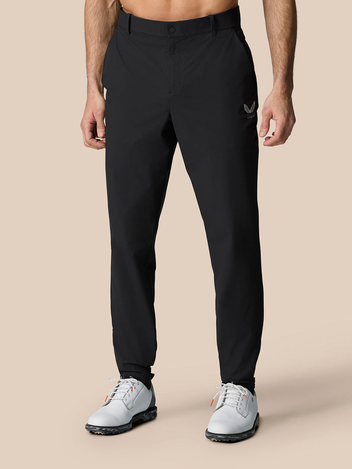 Front view of man in black Golf Pinnacle trousers with belt and white golf shoes.
