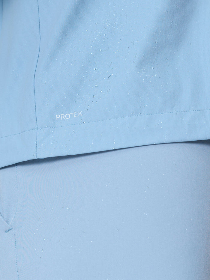 Close-up of water beading on sky blue Flex Jacket fabric showing ProTek water resistance.