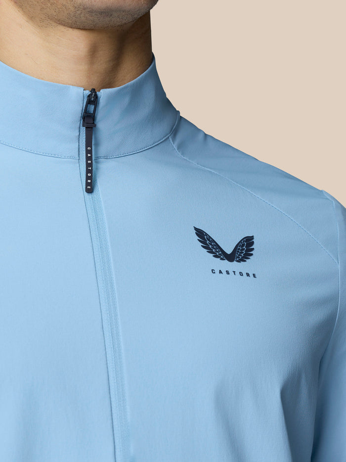 Close-up of sky blue Golf Flex Jacket with front zipper and Castore logo on the left chest.