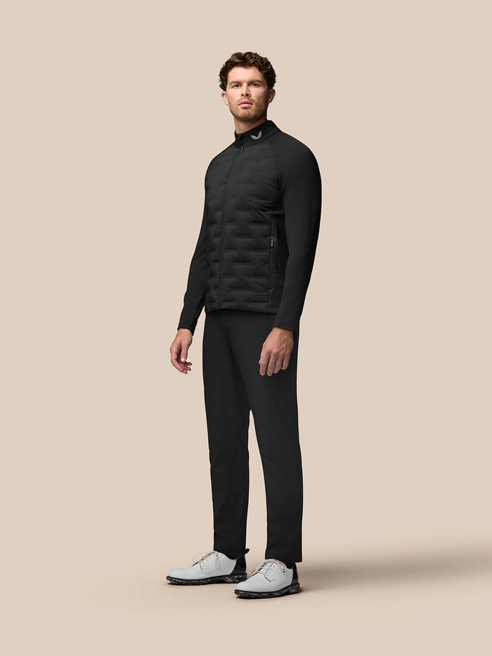 Front view of a male model wearing a black Golf Pinnacle Jacket with quilted front panels and stand collar