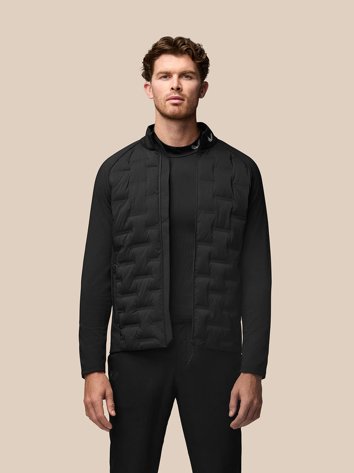 Male model wearing black Golf Pinnacle Jacket with quilted front panels stand collar and front zip.