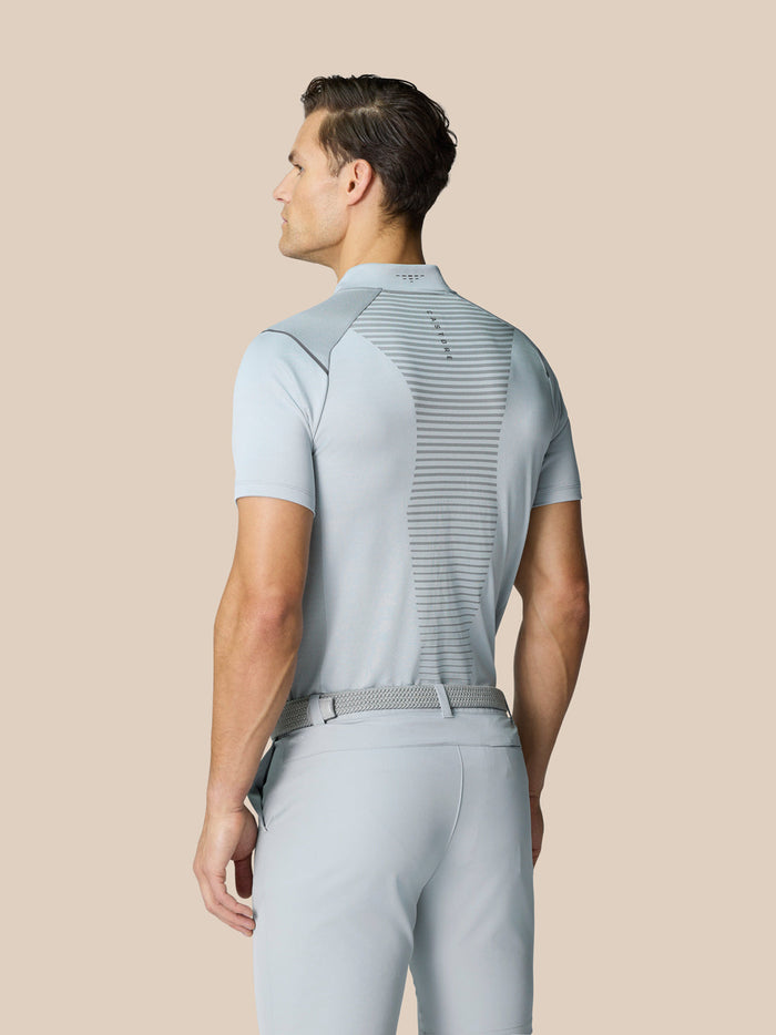Back view of a model wearing a light grey Pinnacle Golf LVS Polo with a striped back panel and logo
