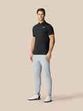 Male model wearing black Club Graphic Polo with golf ball print and light gray pants.