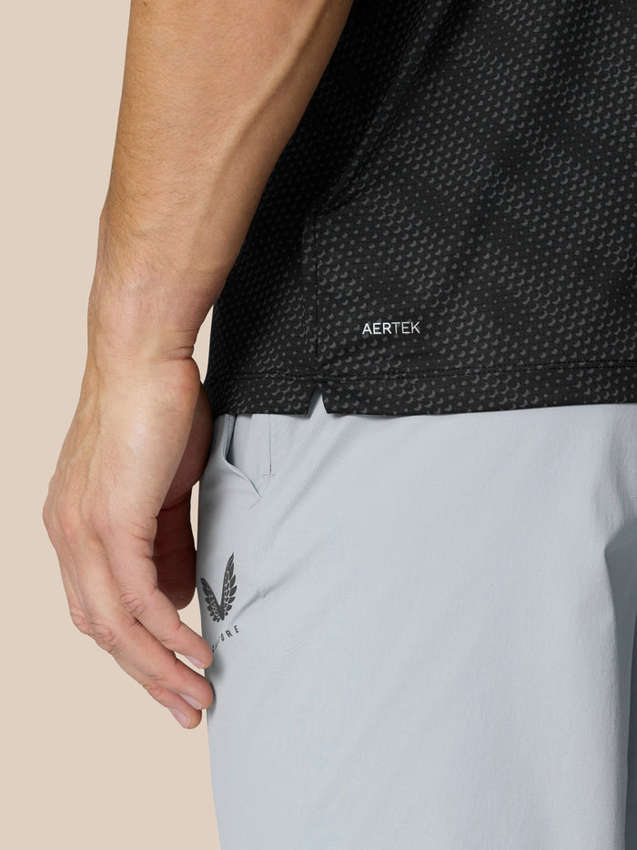 Close up of black Club Graphic Polo texture showing dotted pattern with AERTEK label at the hem