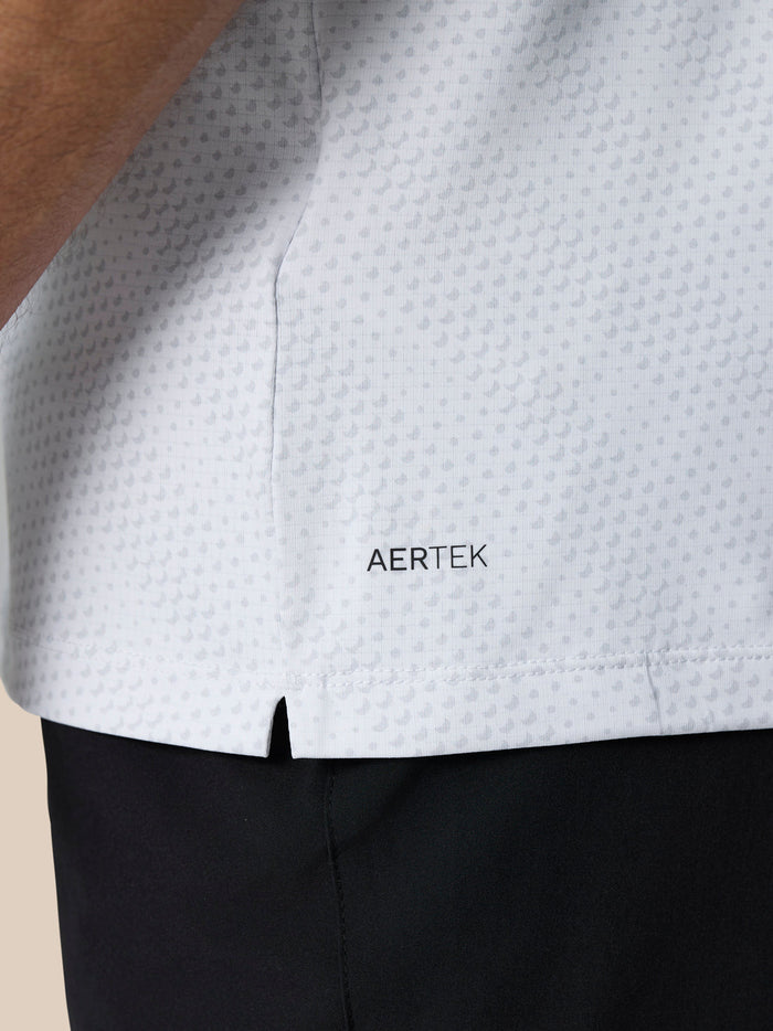 Close-up of white polo lower back showing AERTEK branding and a small side slit.