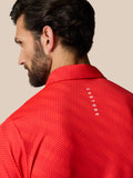 Back view of a man in a red dotted polo with Castore branding along the upper back