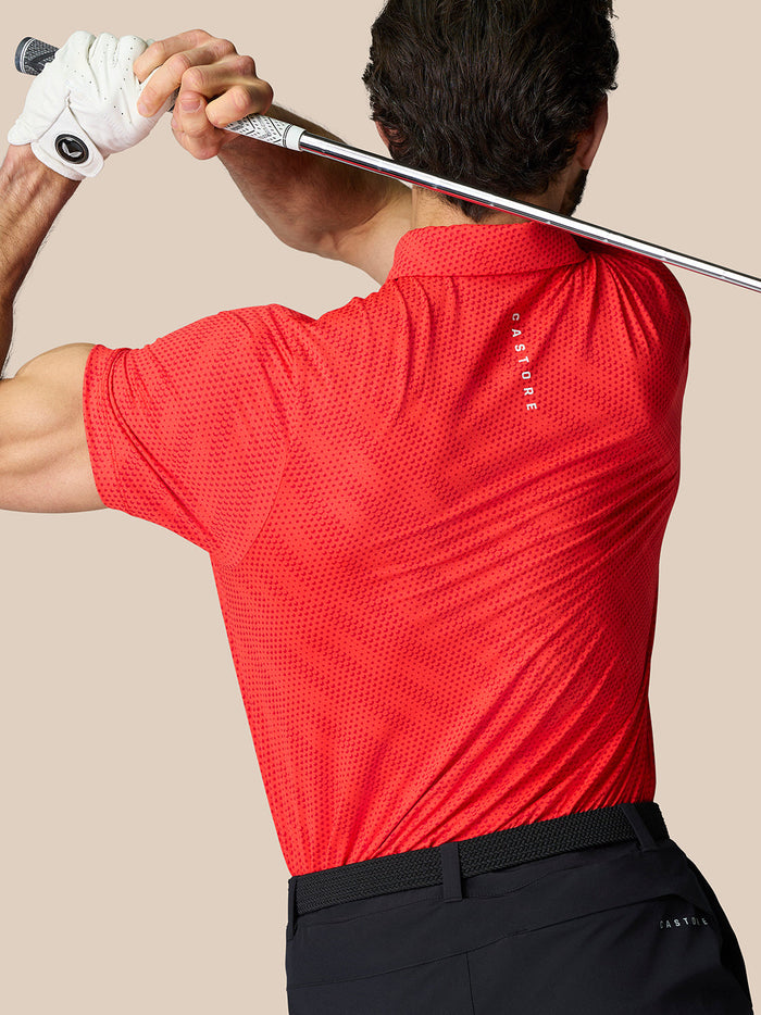 Rear view of a man in a red dotted polo with Castore branding on the upper back