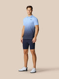 Male model wearing sky blue Club Graphic Polo with ombre gradient and chest logo, paired with dark shorts.