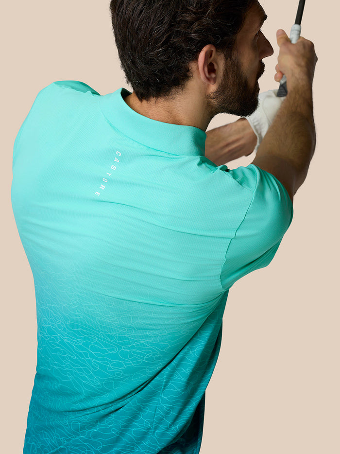 Back view of a man in a light aqua Club Graphic Polo with an ombre pattern and Castore branding along the upper back