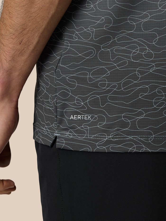 Close-up of the polo’s lower back showing the abstract squiggle print on dark fabric with AERTEK branding on the shorts.