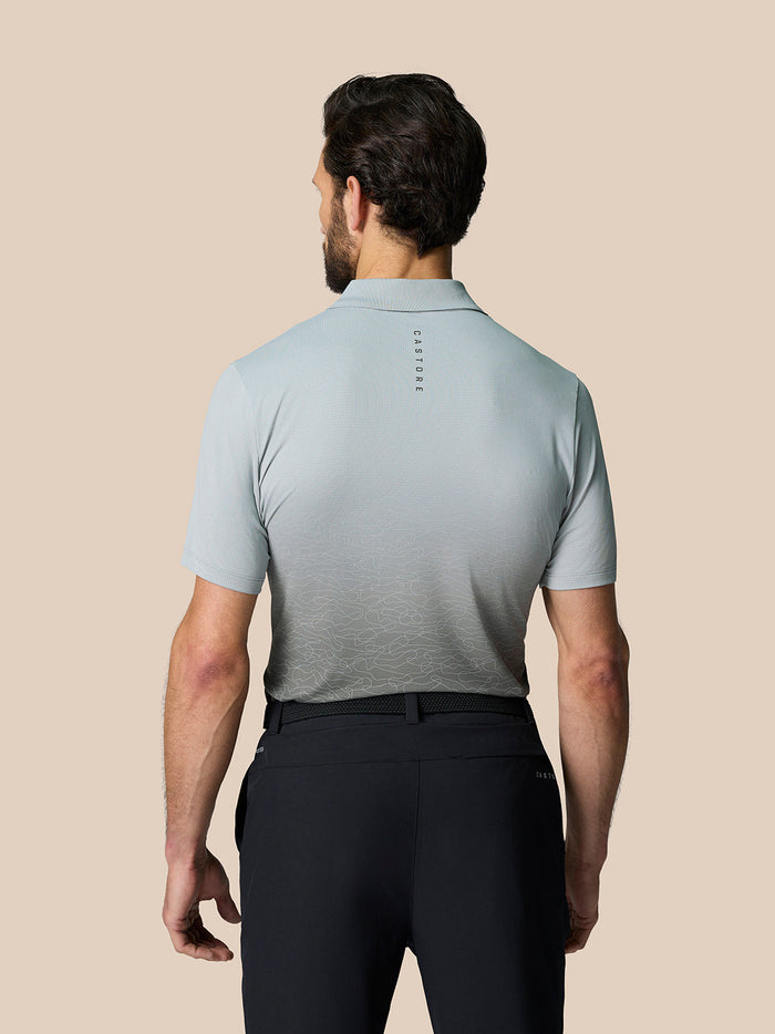 Back view of a man wearing a light grey Club Graphic Polo with an ombre lower panel and Castore branding on the upper back.