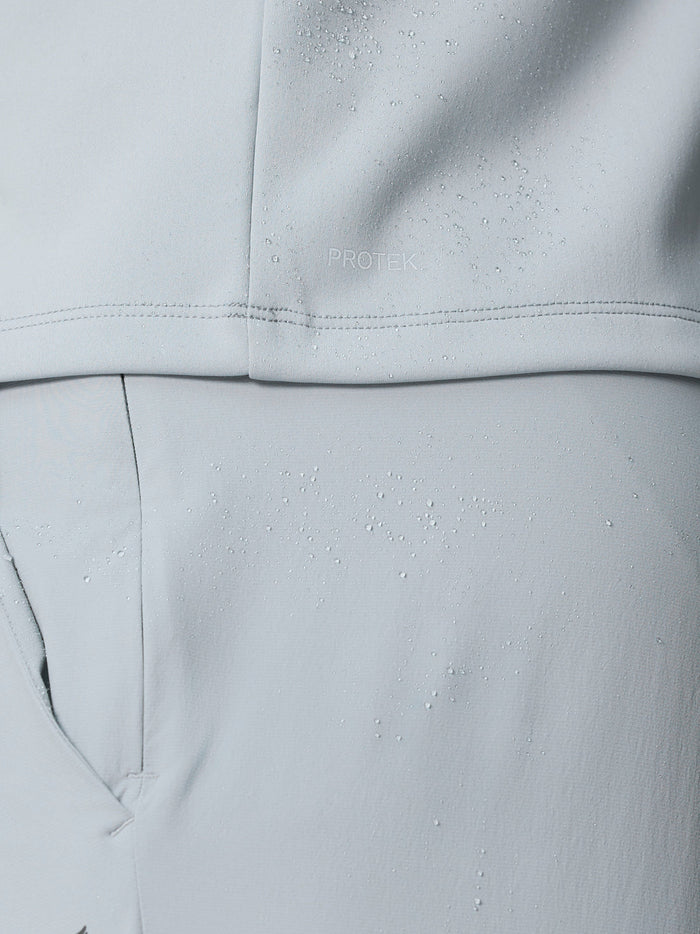 Close-up of light grey ProTek golf gilet fabric with water droplets and clean seam lines