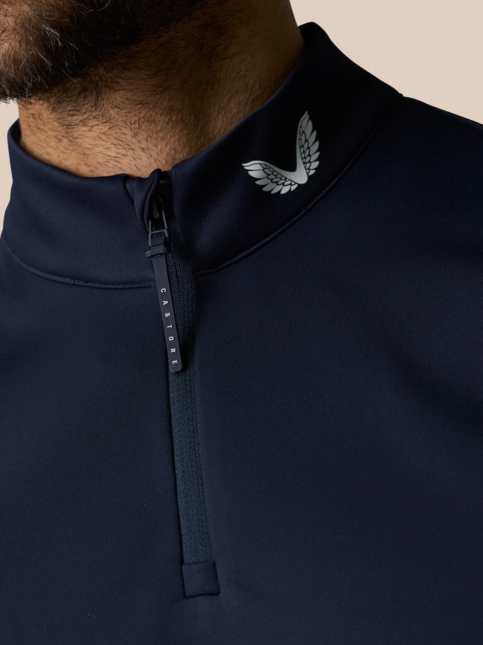 Close up of navy Club Classic half zip gilet collar showing zipper pull and Castore emblem.