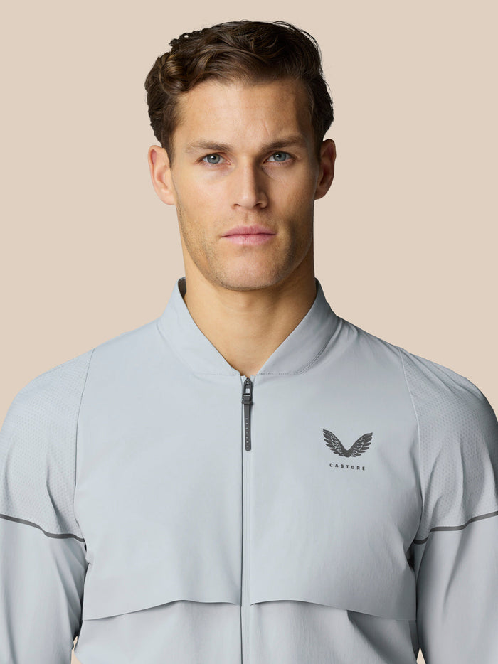 Male model wearing light grey Golf Pinnacle LVS Woven Jacket with zip front and chest logo