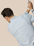 Model wearing Golf Pinnacle LVS Woven Jacket in mid grey, back view with vent mesh and dropped hem.