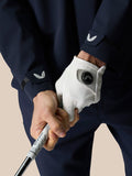 Close-up of a golfer in a midnight navy LVS woven jacket gripping a golf club, white glove on hand and wing logo on the cuff.