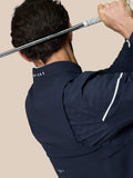 Golfer in navy Golf Pinnacle LVS Woven Jacket swinging a club with back vented sleeves and Castore branding on the collar