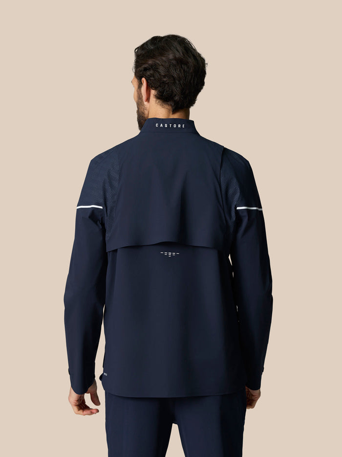 Back view of man in navy Golf Pinnacle LVS Woven Jacket showing vented back panel and Castore logo on the collar