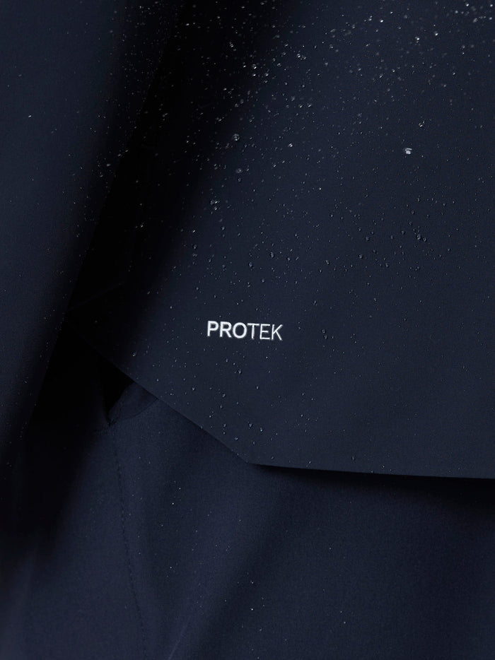 Midnight navy Golf Pinnacle LVS Woven Jacket fabric close-up with water droplets and ProTek logo