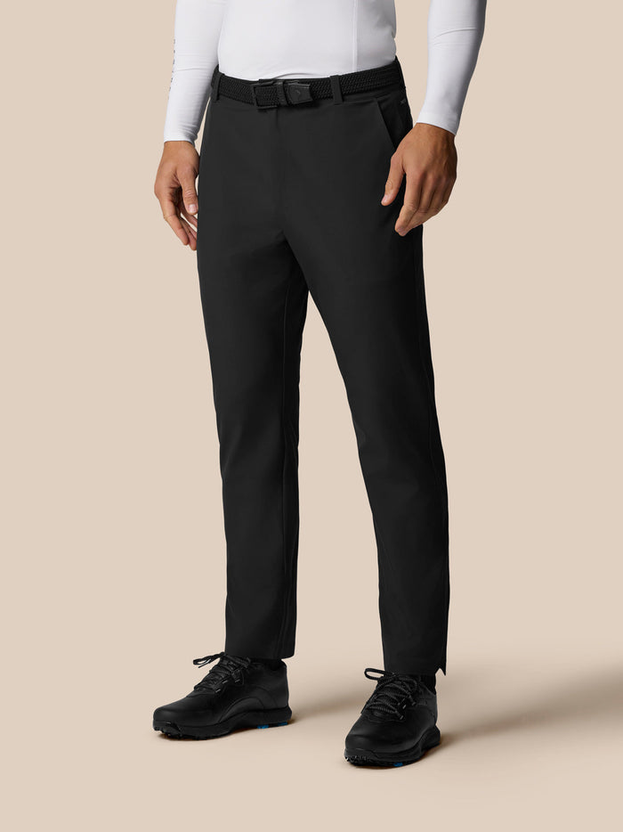 Male model wearing black Golf Pinnacle Winter Trousers with woven belt and front pockets.