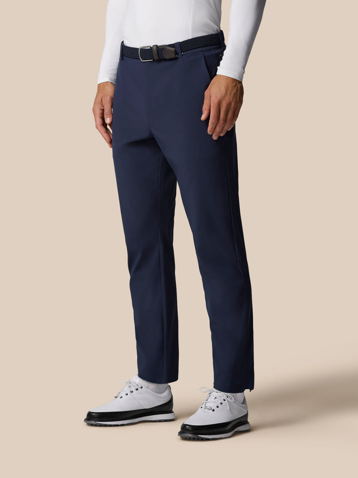 Model wearing midnight navy golf winter trousers with a black belt and white top