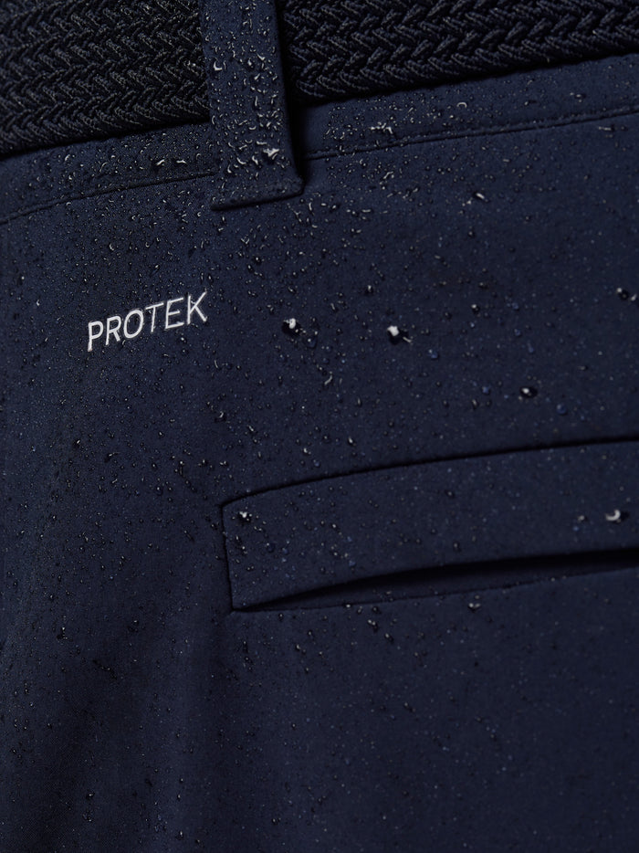 Close up of navy fabric with PROTEK branding and water droplets on the water resistant pocket area.
