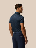 Back view of a man wearing a navy striped golf polo with Castore branding along the back