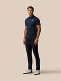 Front view of a man in a navy striped golf polo with a button collar and Castore logo on the left chest