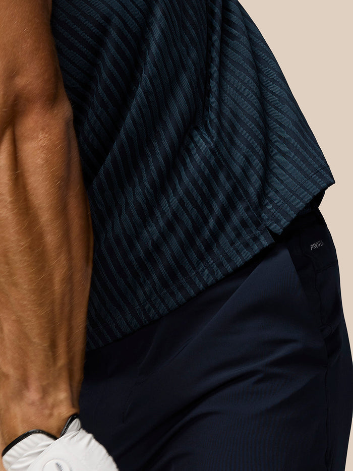 Close up of navy striped knit polo fabric at the waist with a dark belt and trousers