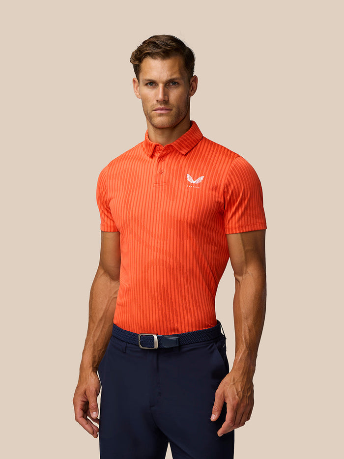 Man wearing Golf Pinnacle Glow Polo in bright orange with striped knit and Castore logo on left chest