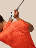 Golfer in Pinnacle Glow Polo bright orange with Castore logo during swing