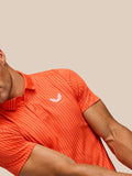 Side-angle view of a man in bright orange striped Golf Pinnacle Glow Polo with Castore logo.