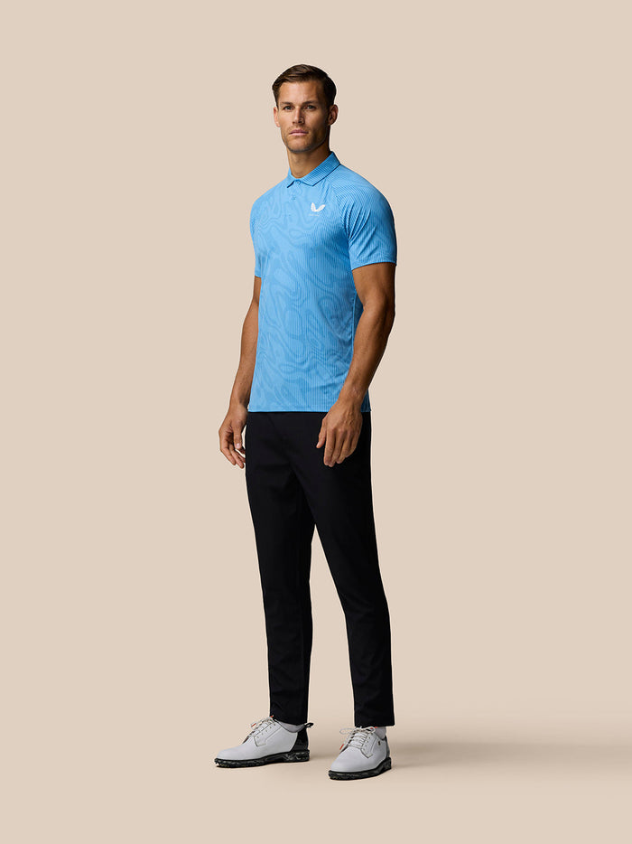 Male model wearing light blue Golf Club Glow Printed Polo from side showing the allover print and three-button placket