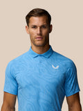 Male model wearing light blue Golf Club Glow Printed Polo with subtle vertical pattern and Castore logo on left chest.