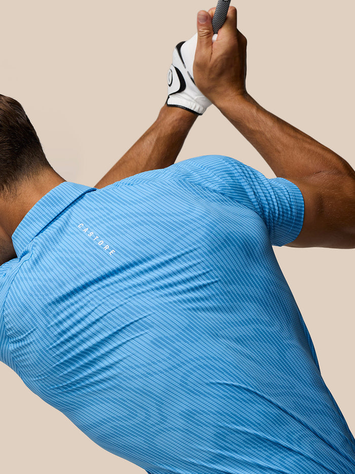 Male golfer wearing cool blue Glow Printed Polo with three button placket and Castore logo on left chest