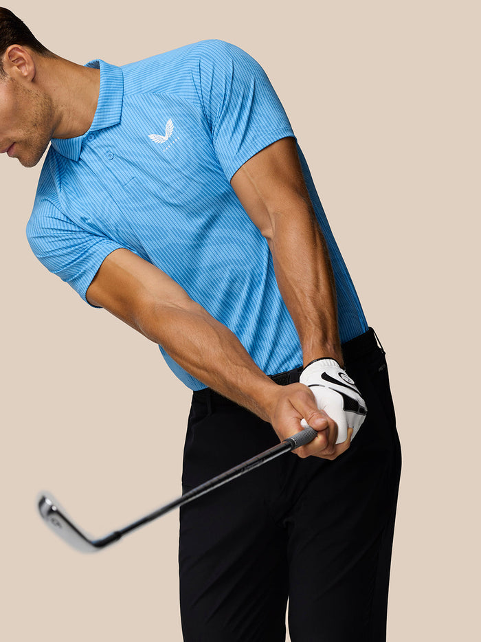 Back and side view of male in blue Glow Polo with AerTek label at the hem and black shorts.