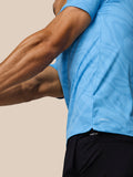 Side view of male golfer wearing blue Golf Club Glow Polo during swing, showing knit pattern and motion.