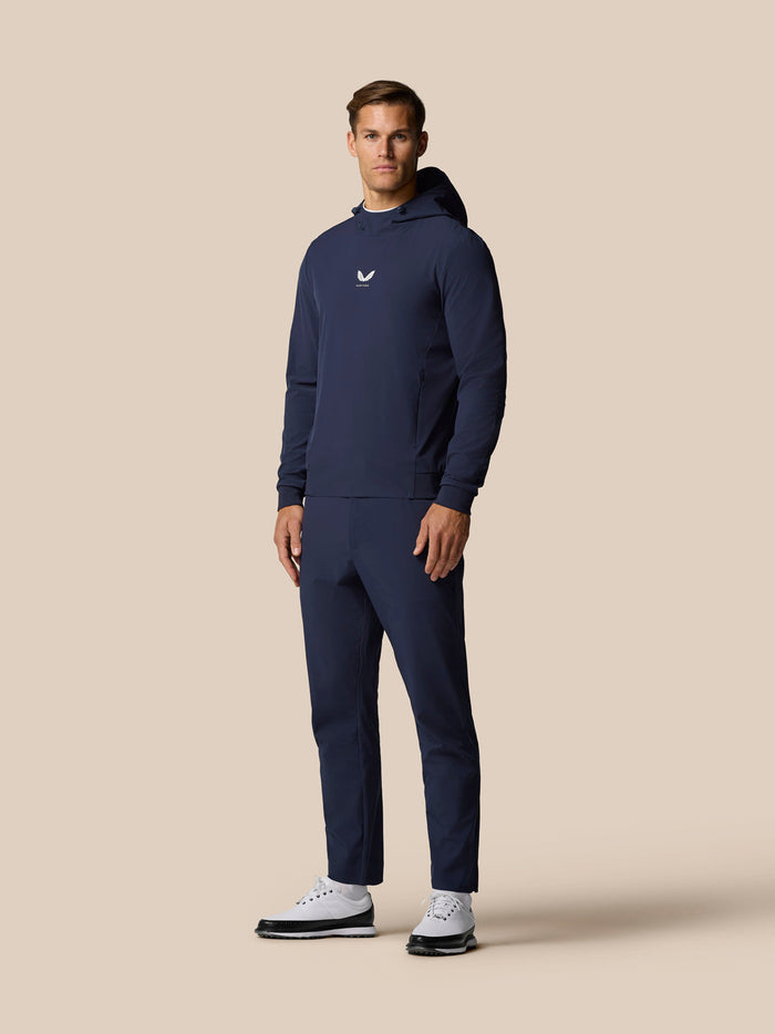 Full body shot of man in midnight navy golf apparel including hoodie and matching pants with white sneakers