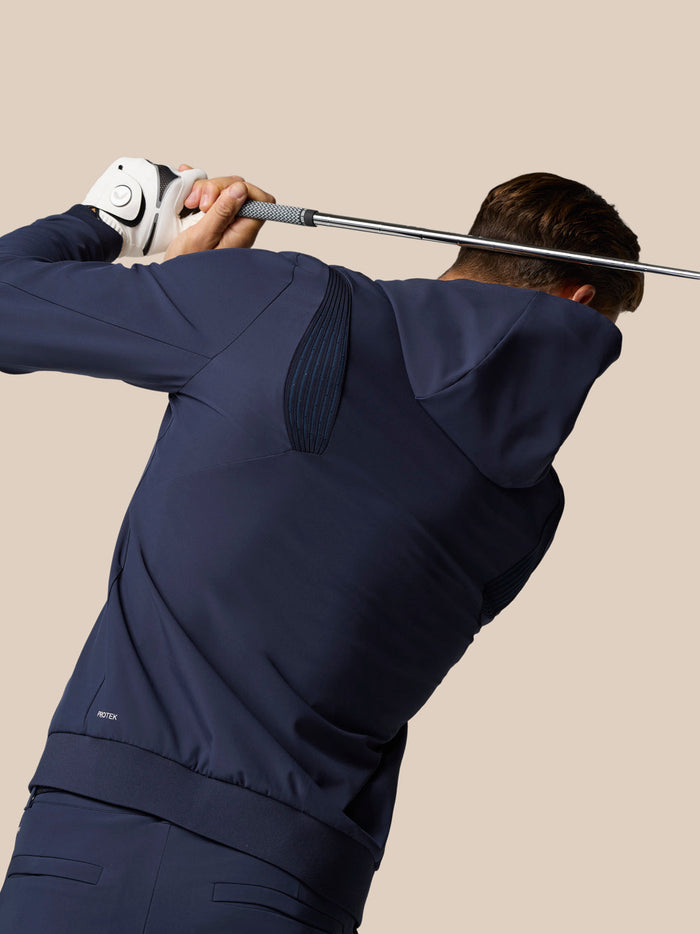 Golf Pinnacle Performance Hoodie in midnight navy worn by a golfer during a swing, highlighting flexible movement panels.