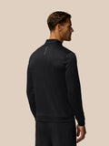 Back view of a man wearing a black all over print golf quarter zip top with Castore branding on the back and left chest