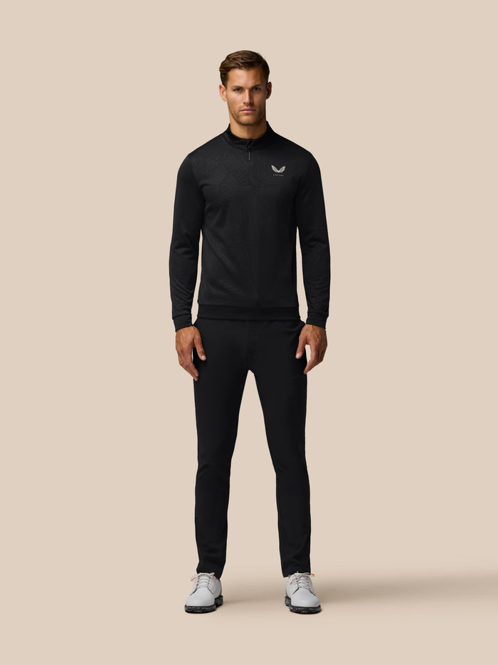 Man wearing black all over print golf top with quarter zip and Castore logo on chest